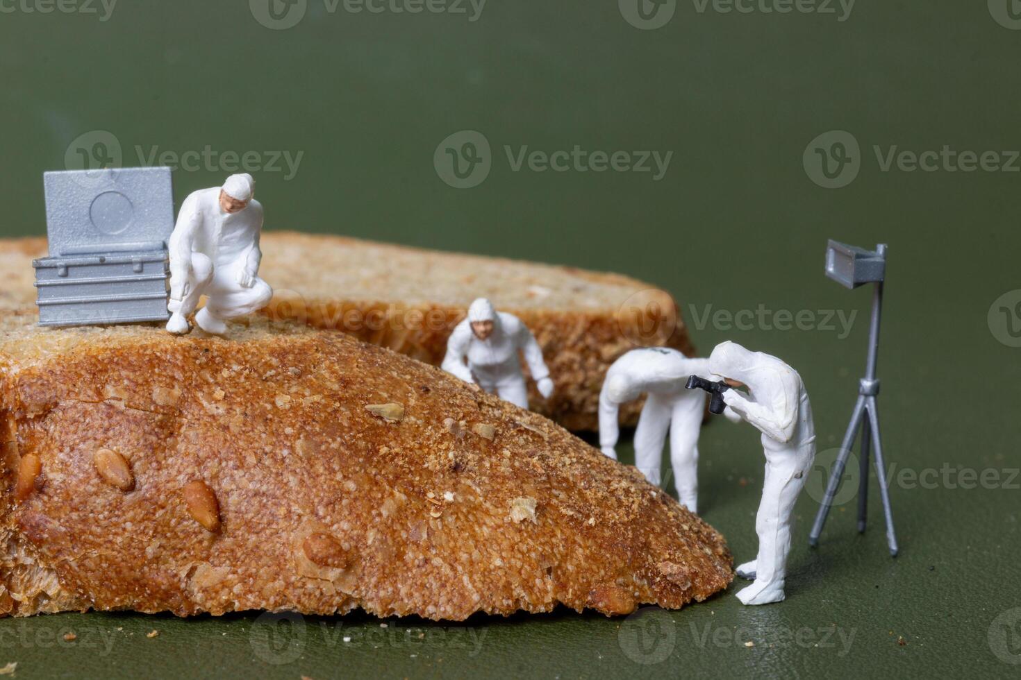 Miniature figurines dressed as forensic investigators examining bread slices with equipment photo