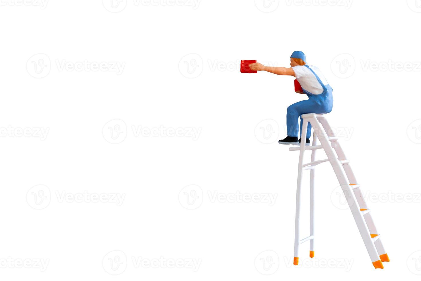 A miniature figurine of a painter seated on a ladder, holding a paint can and brush isolate on white back ground with clipping path photo