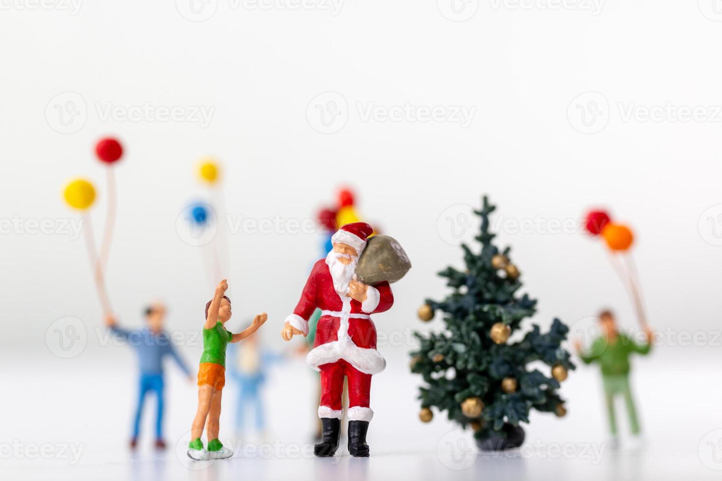 Miniature Santa Claus holding a gift surrounded by children and colorful balloons photo