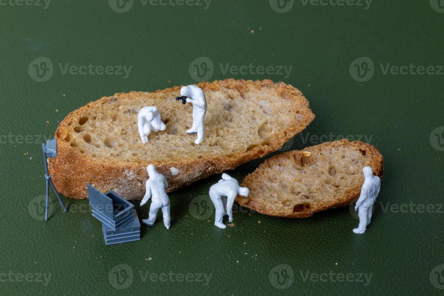 Miniature figurines dressed as forensic investigators examining bread slices with equipment photo
