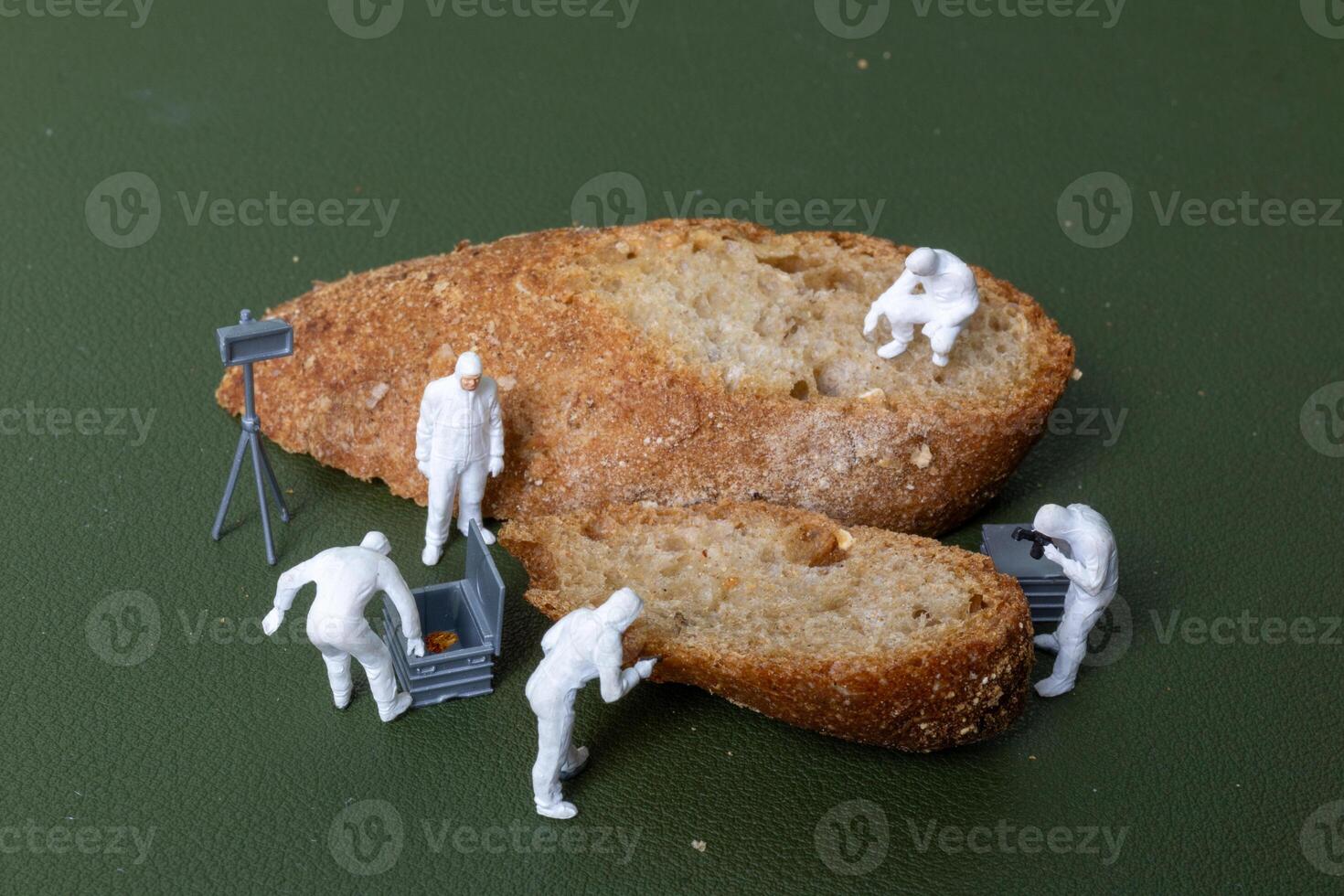 Miniature figurines dressed as forensic investigators examining bread slices with equipment photo