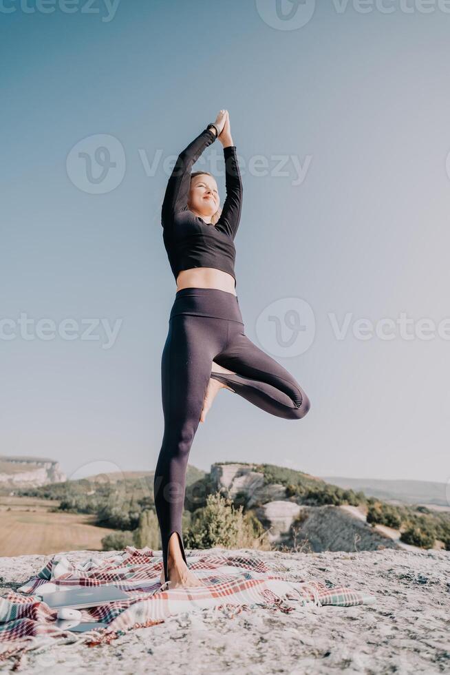 Woman Practicing Yoga in Tree Pose on a Mountaintop photo