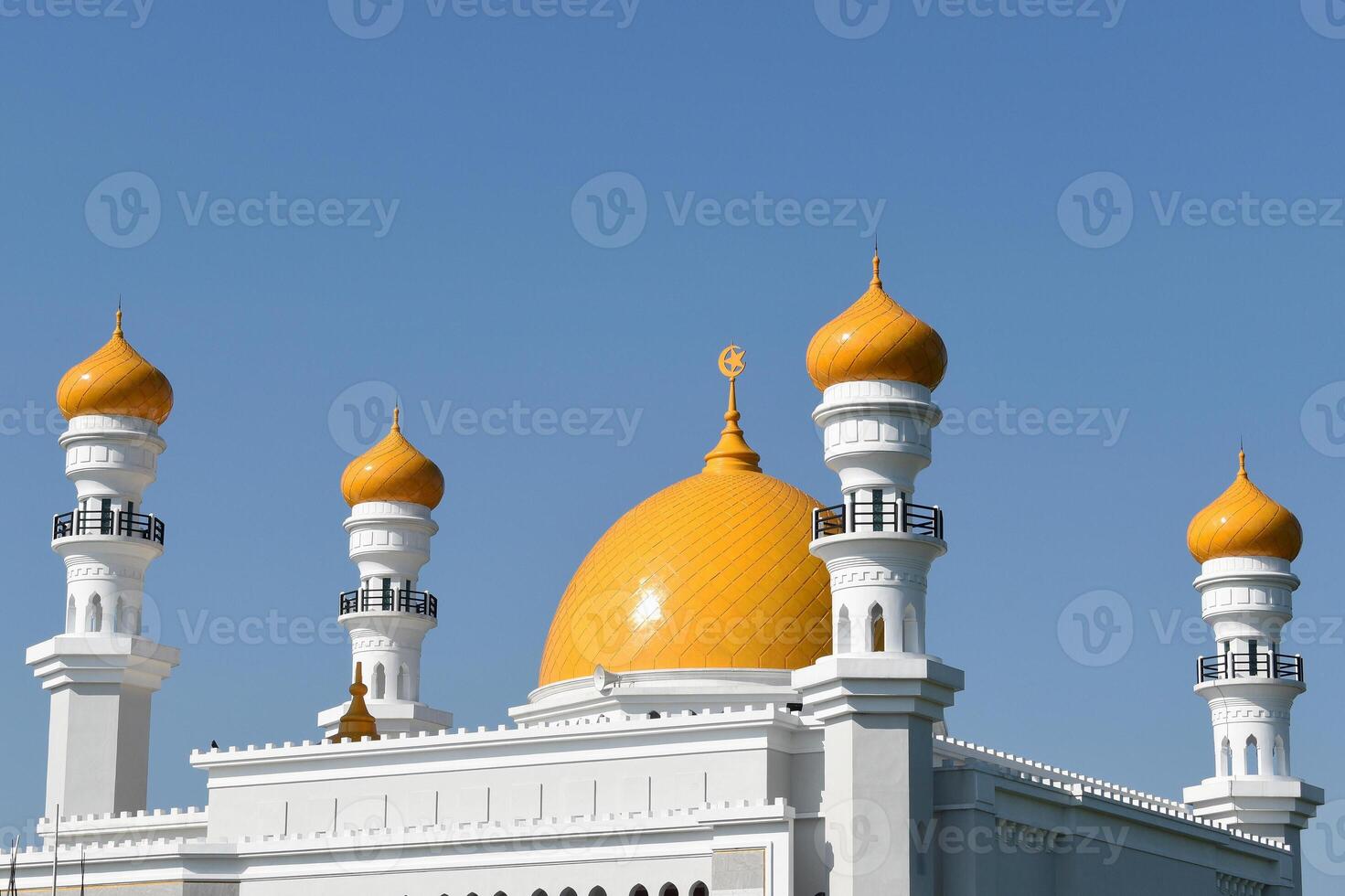 Beautiful white mosque with yellow tops with clear blue sky in the background photo
