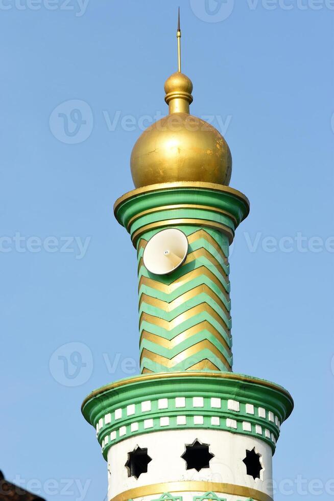 A green white mosque minaret with gold top photo