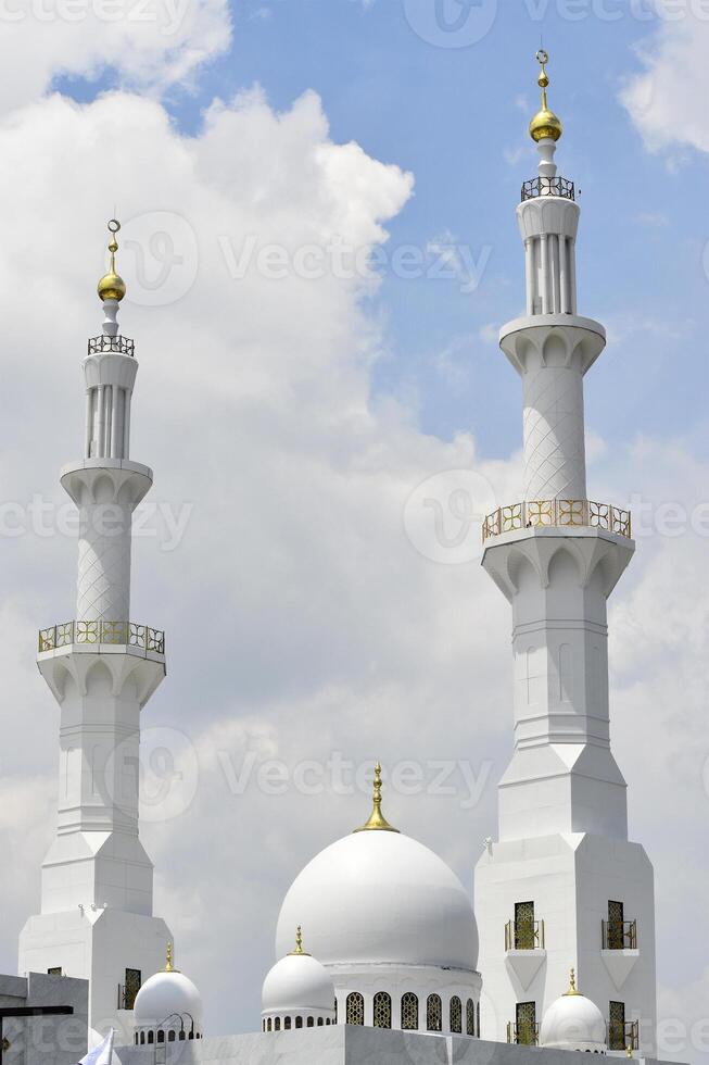 The domes and the two towers of a white grand mosque photo