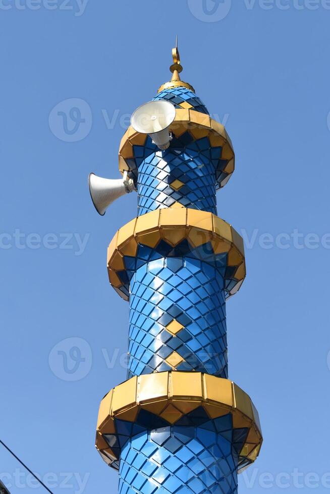 Beautiful mosque minaret with gold and blue colors equipped with loudspeakers photo