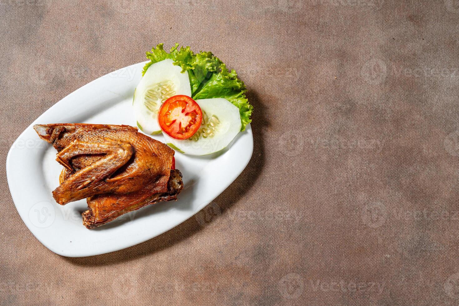 Bebek Goreng, Traditional Fried Duck. Popular Menu came from Madura, East Java. served with sambal, cucumber, tomato and lettuce. photo