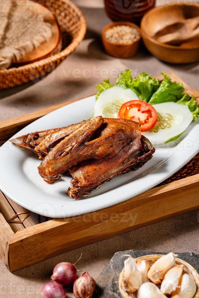 Bebek Goreng, Traditional Fried Duck. Popular Menu came from Madura, East Java. served with sambal, cucumber, tomato and lettuce. photo