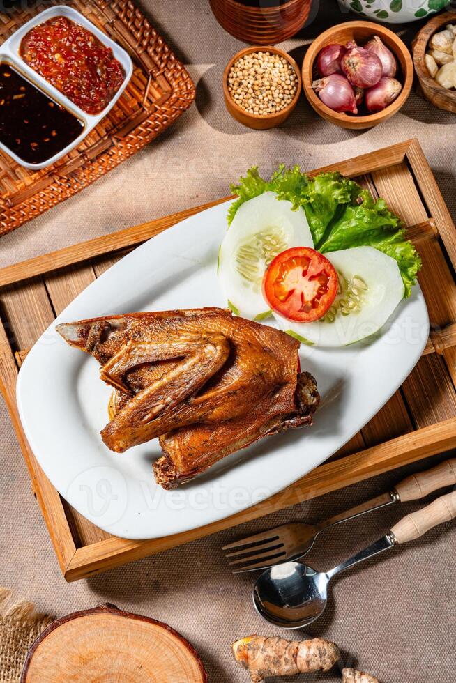 Bebek Goreng, Traditional Fried Duck. Popular Menu came from Madura, East Java. served with sambal, cucumber, tomato and lettuce. photo