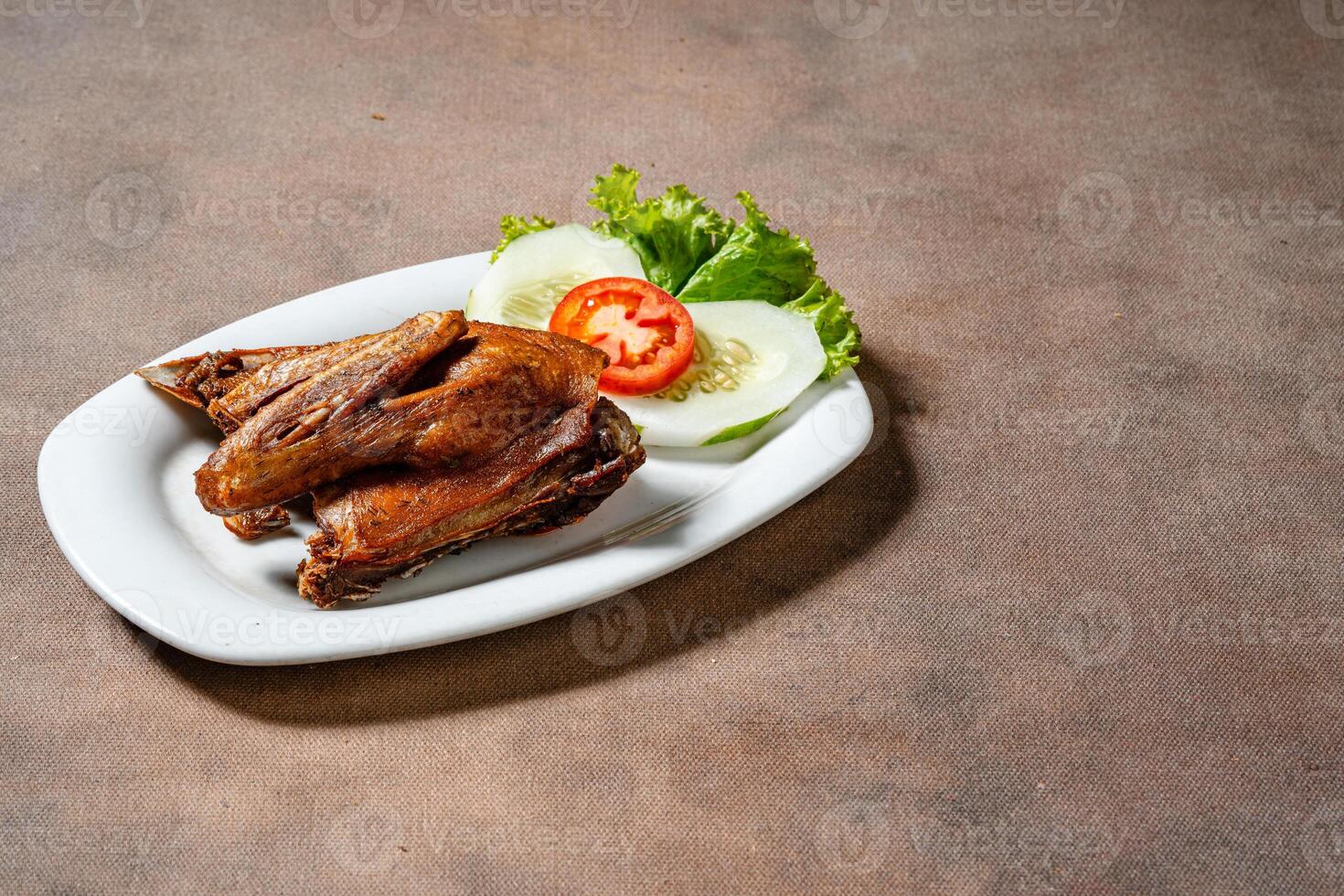 Bebek Goreng, Traditional Fried Duck. Popular Menu came from Madura, East Java. served with sambal, cucumber, tomato and lettuce. photo