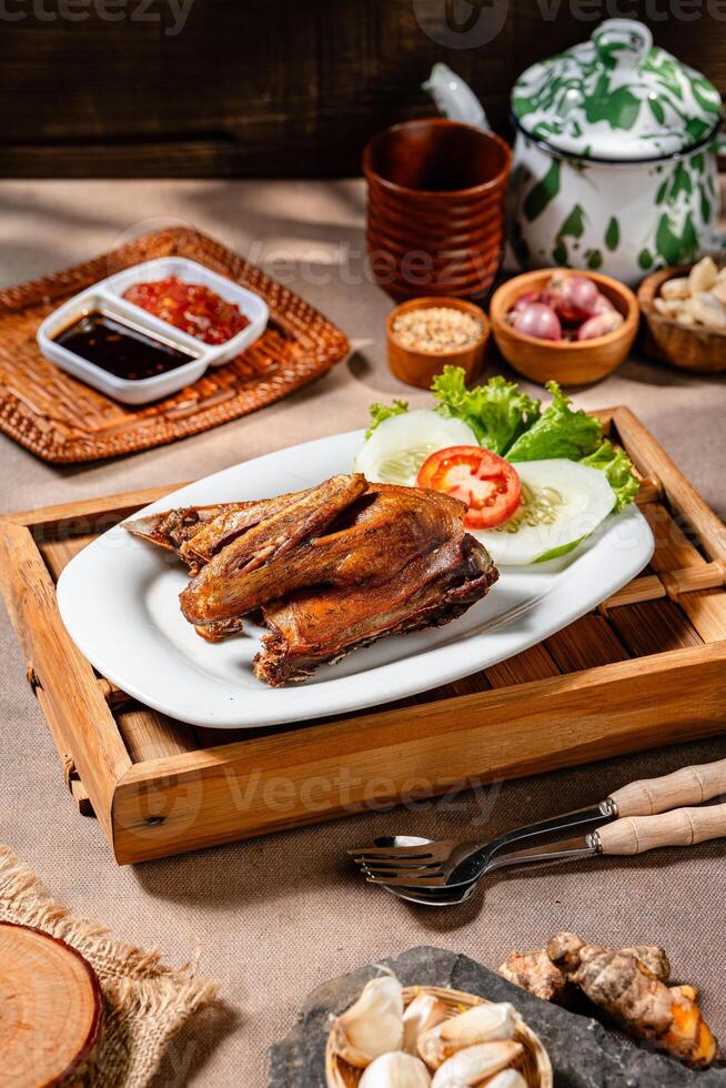 Bebek Goreng, Traditional Fried Duck. Popular Menu came from Madura, East Java. served with sambal, cucumber, tomato and lettuce. photo