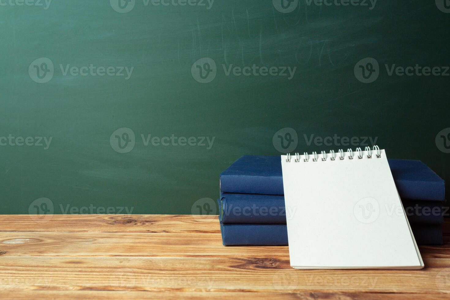 Classroom with blackboard, wooden table and books photo