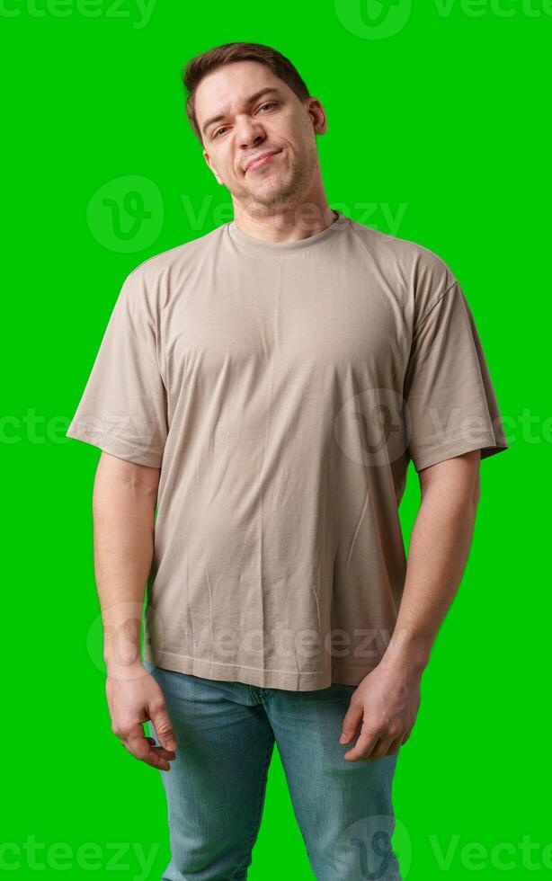 Young man making a disgusted expression while standing against a bright green background photo