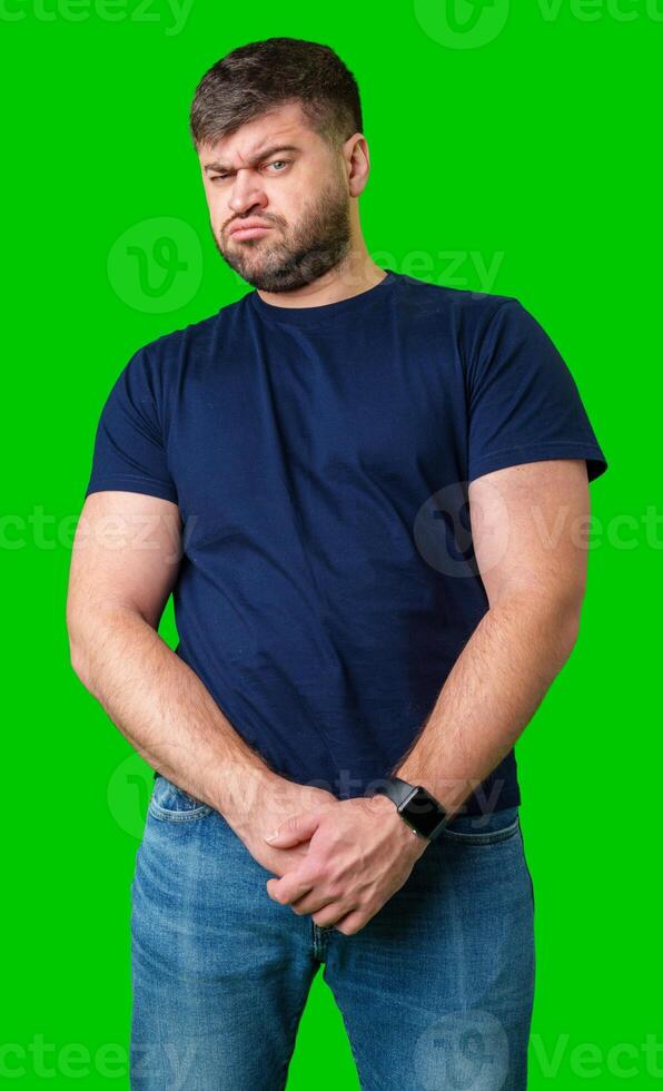 Man standing with a thoughtful expression in a casual outfit against a green background photo