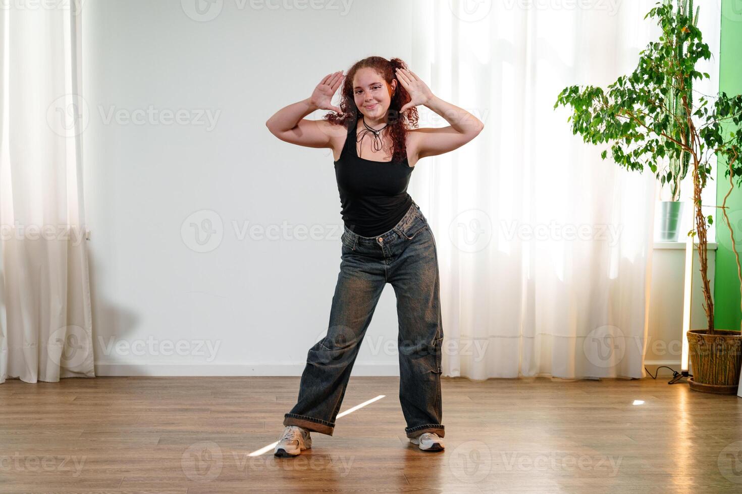 A young woman with curly hair poses for a photo in a studio