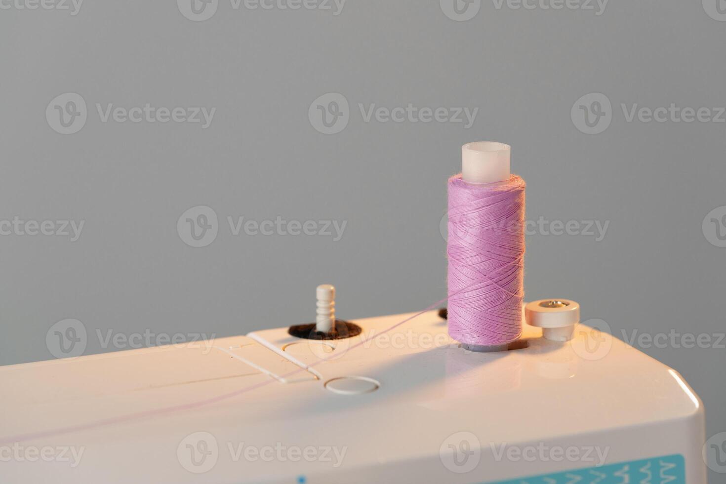 View of a sewing machine with a spool of pink thread placed on top photo