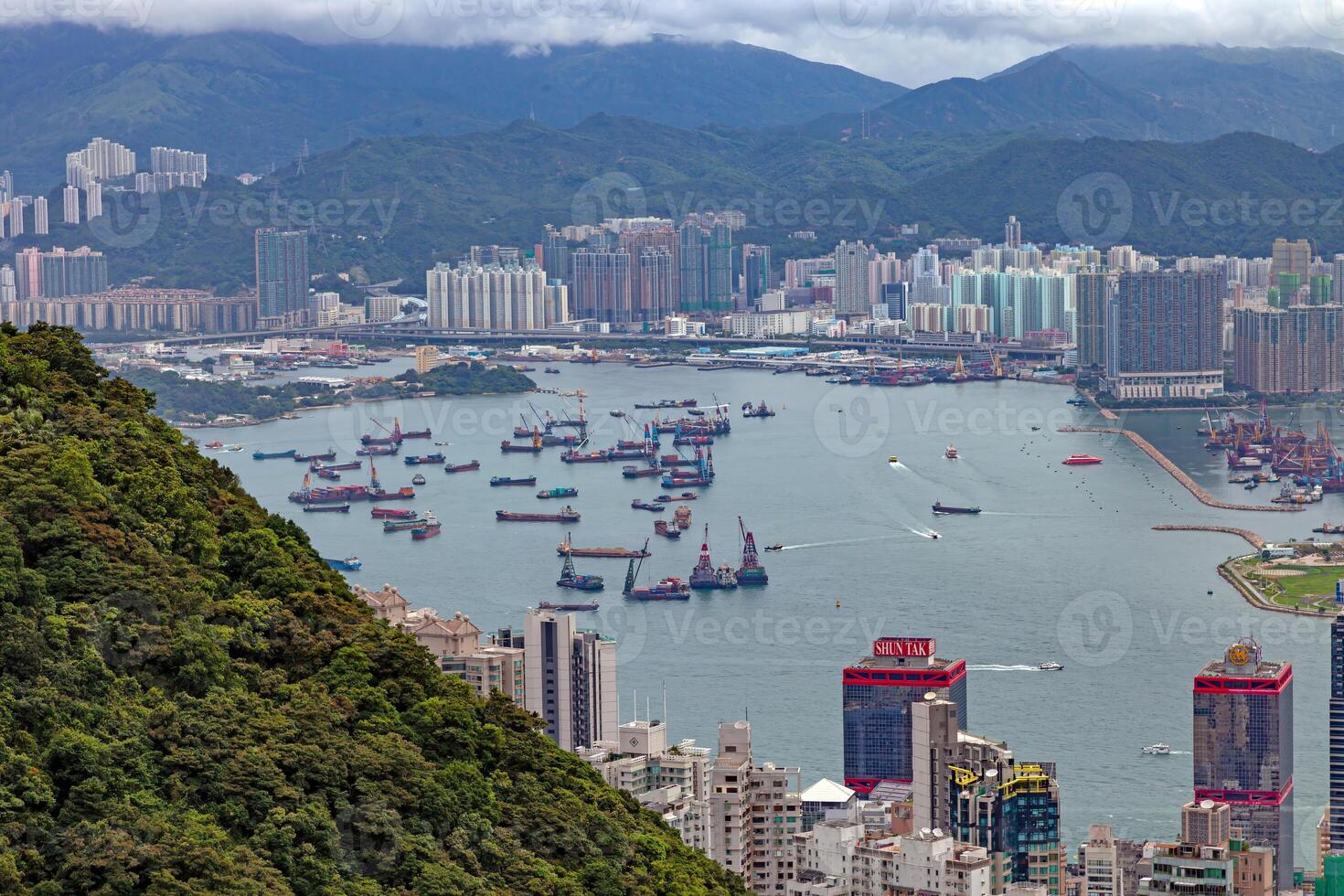 Aerial view of cargo ships anchored near Hong Kong port, with urban skyline and mountains in the background photo