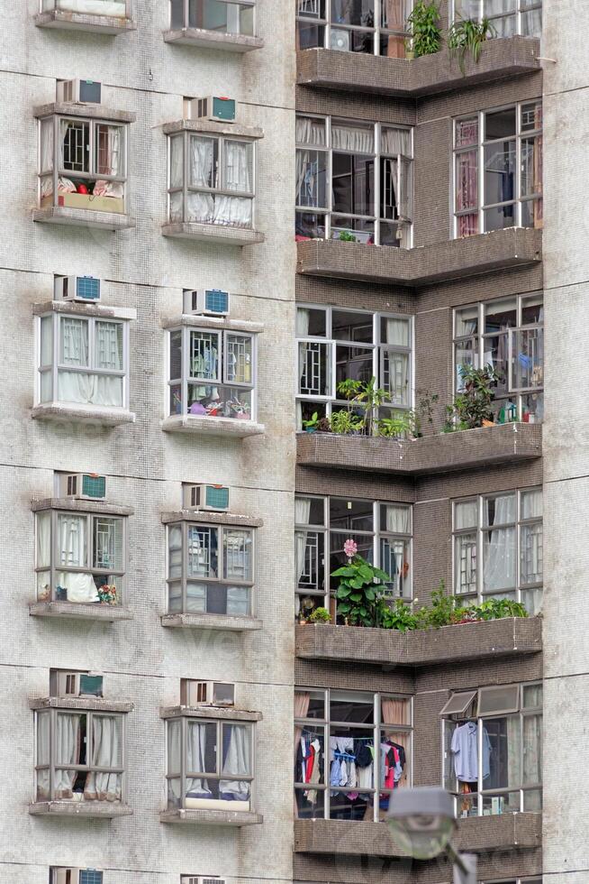 Close-up of a residential building facade with detailed windows, plants, and signs of everyday urban life photo