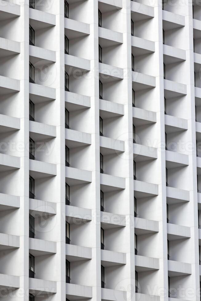Modern high-rise facade with repeating geometric balconies creating a minimal and abstract urban pattern photo