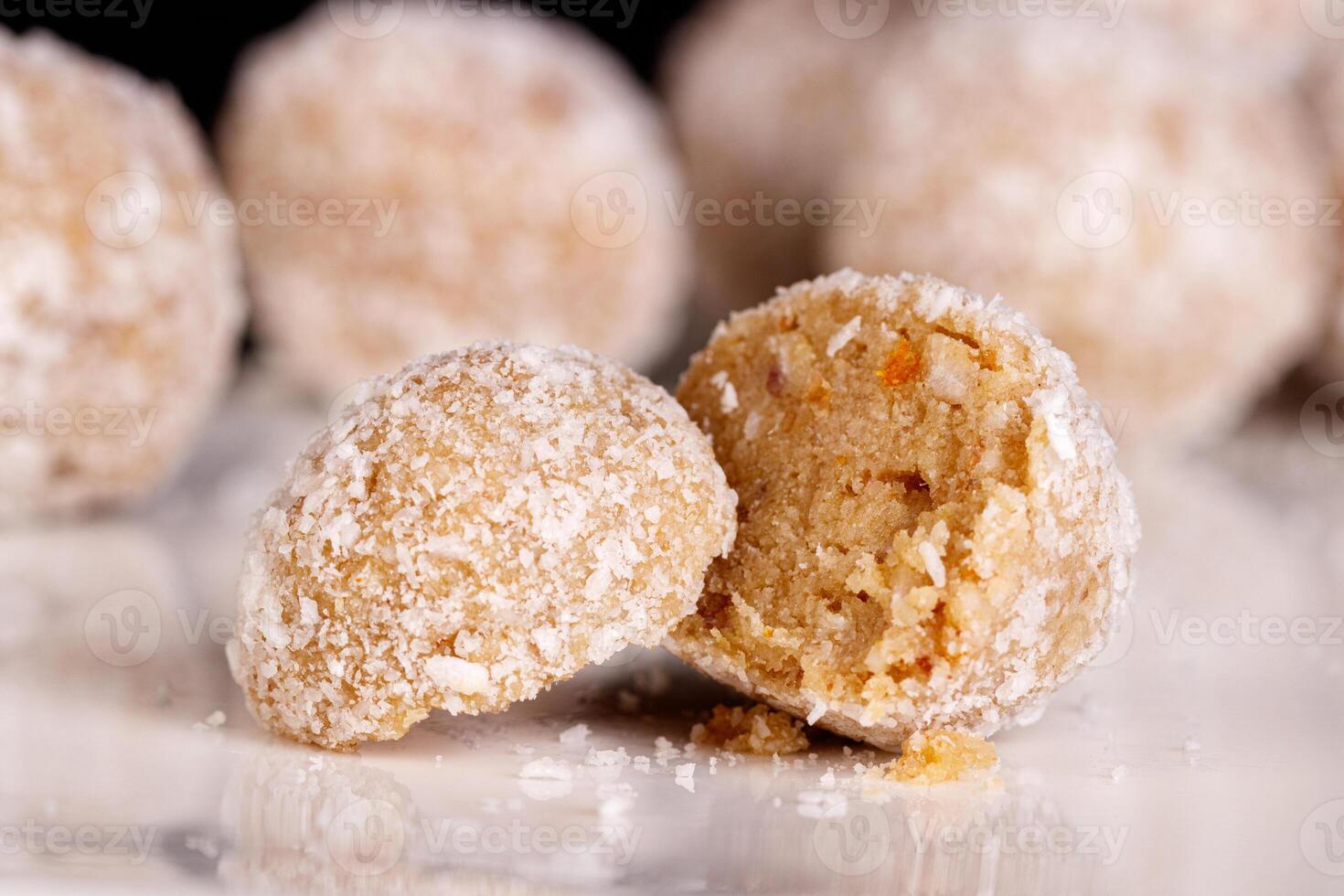 Beautiful sweets with coconut on a white plate on a black background photo