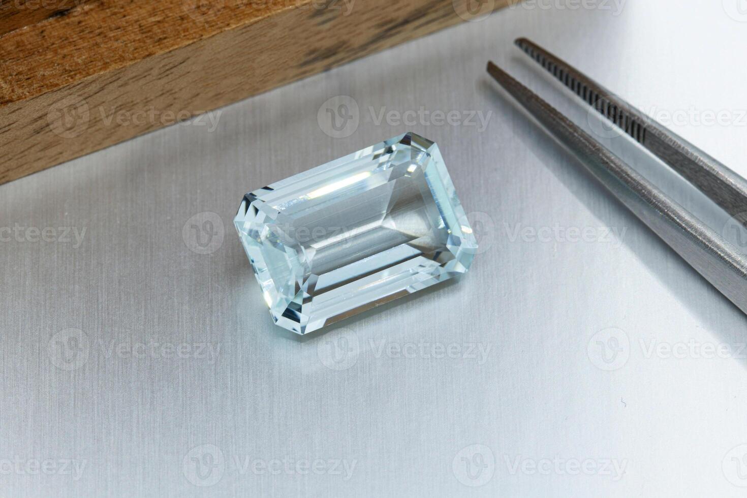 macro mineral faceted stone aquamarine with tweezers on a gray background photo