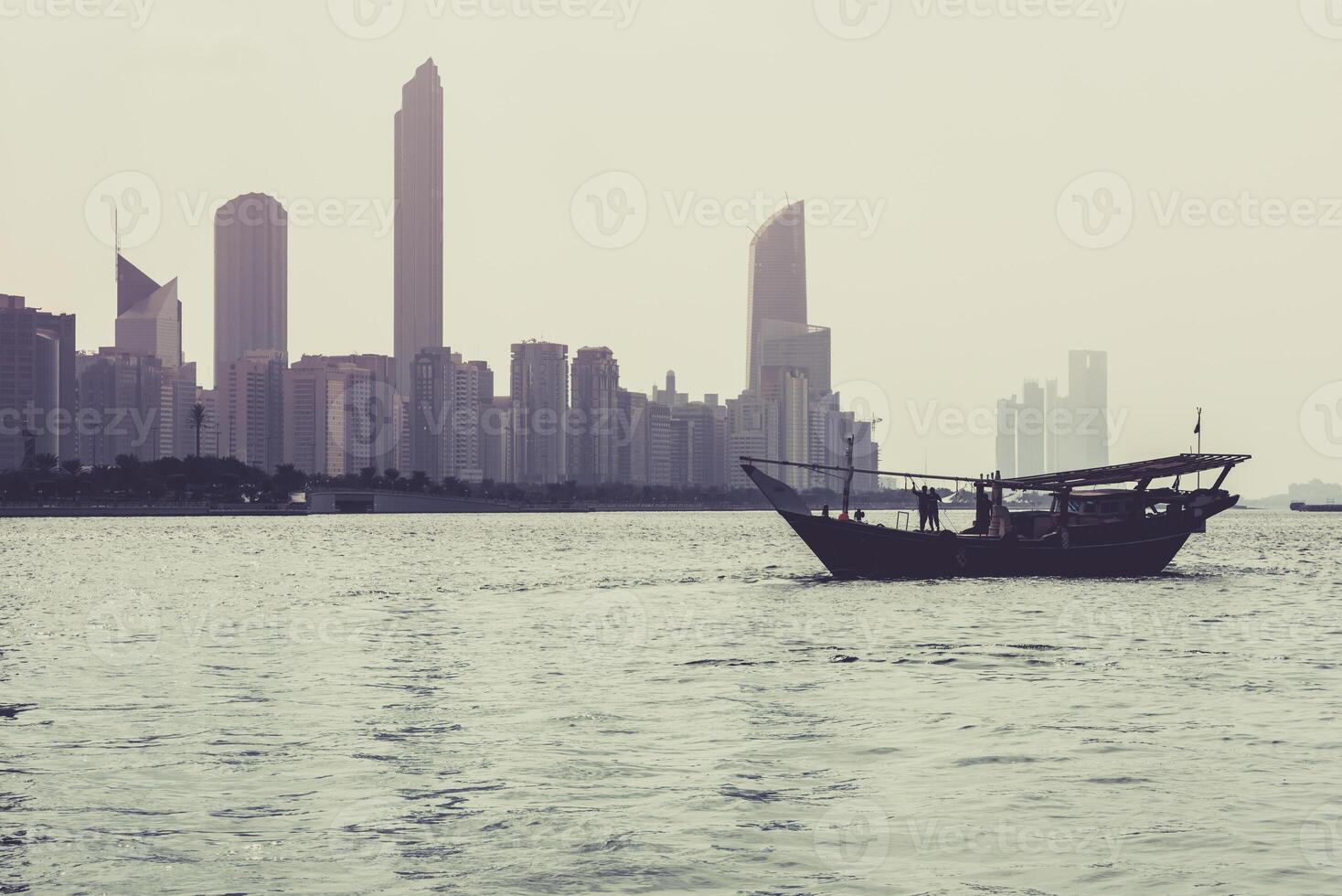 Abu Dhabi buildings skyline with old fishing boat photo