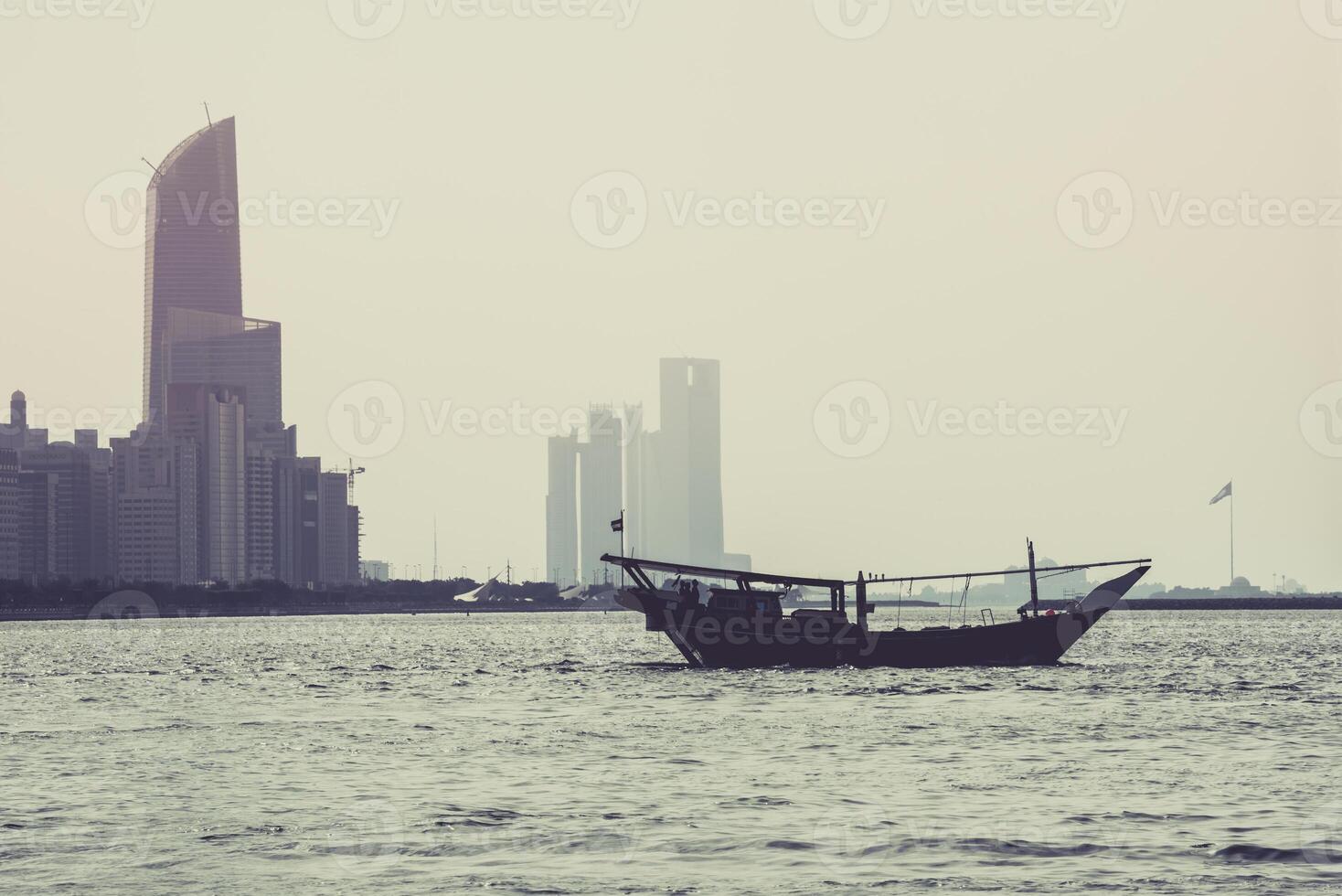 Abu Dhabi buildings skyline with old fishing boat photo