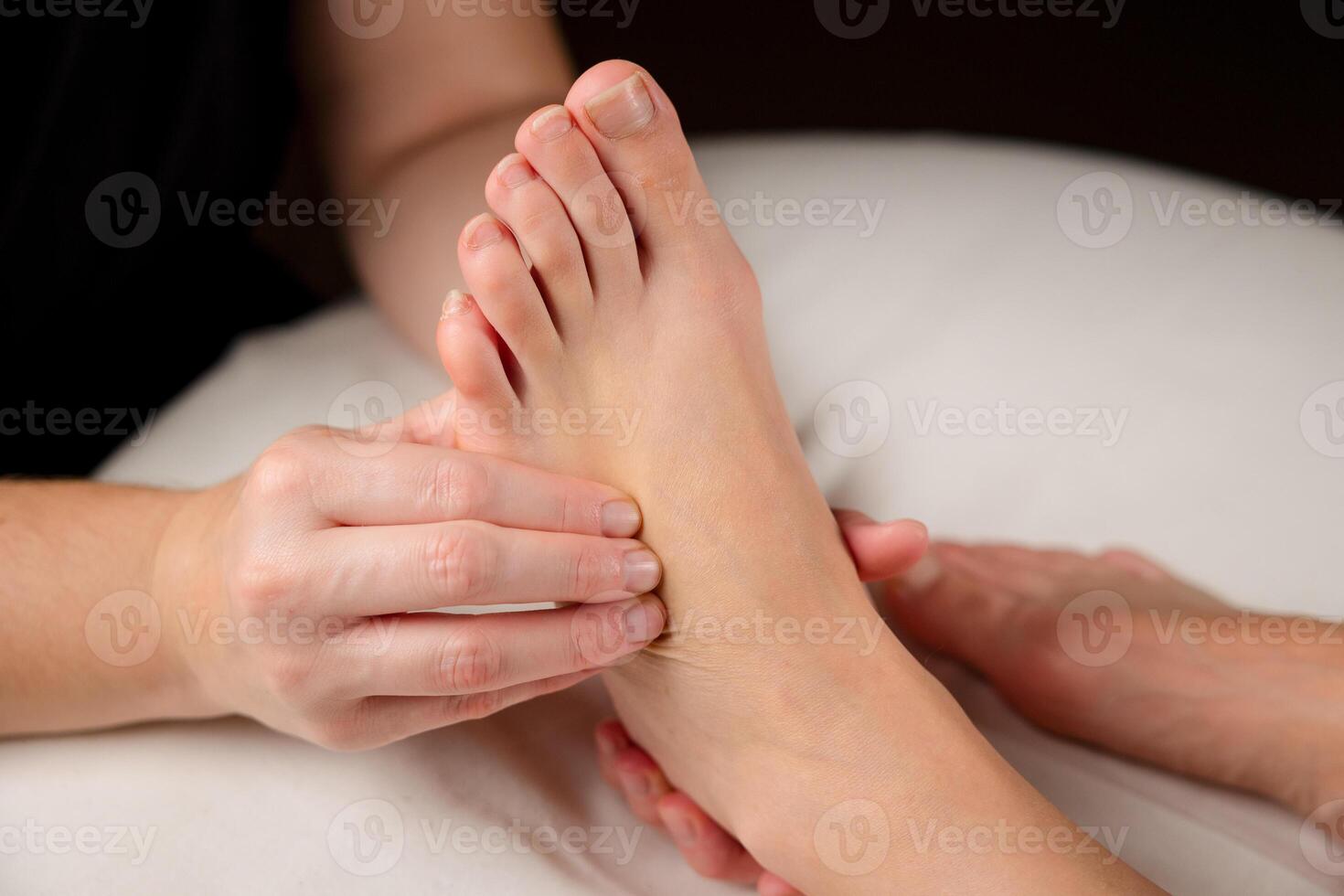 Close up of a therapist hands massaging a client foot. Foot reflexology and relaxation concept photo