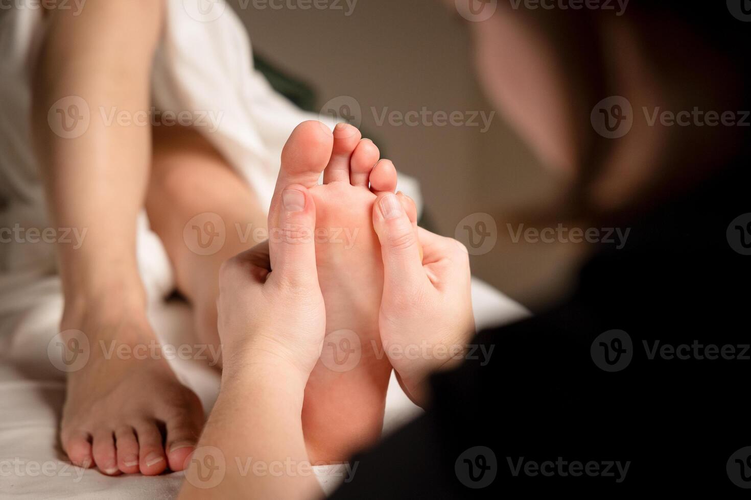 Close up of a therapist hands massaging a client foot. Foot reflexology and relaxation concept photo