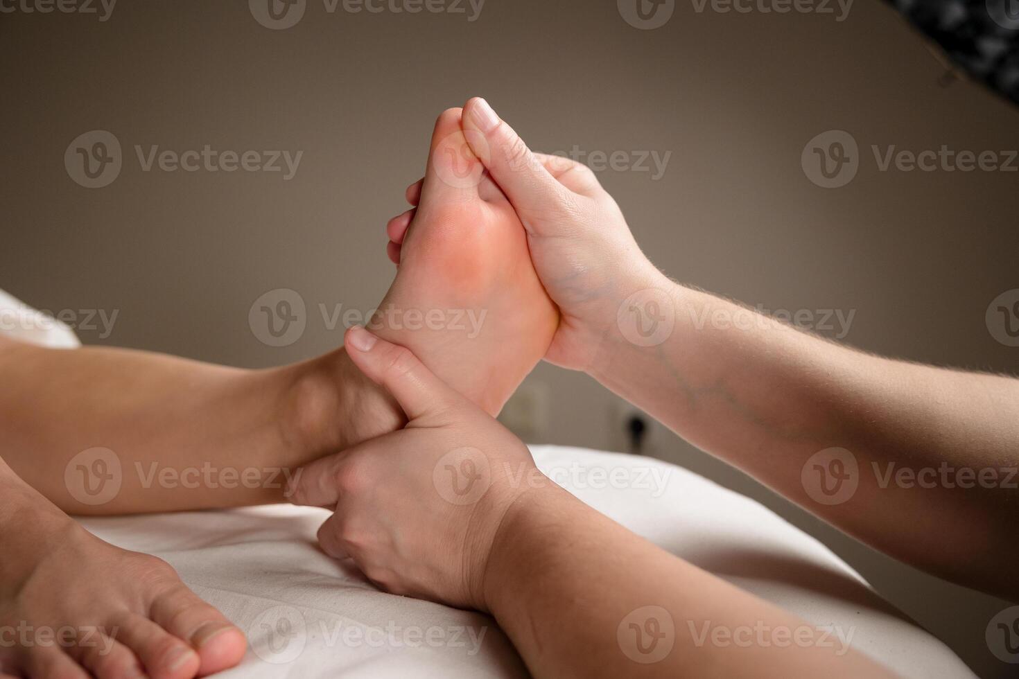 Close up of a therapist hands massaging a client foot. Foot reflexology and relaxation concept photo