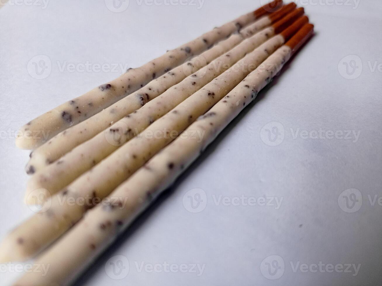 Chocolate biscuit stick coated with milk flavour confectionery and crushed cookies and cream taste isolated on white background. photo