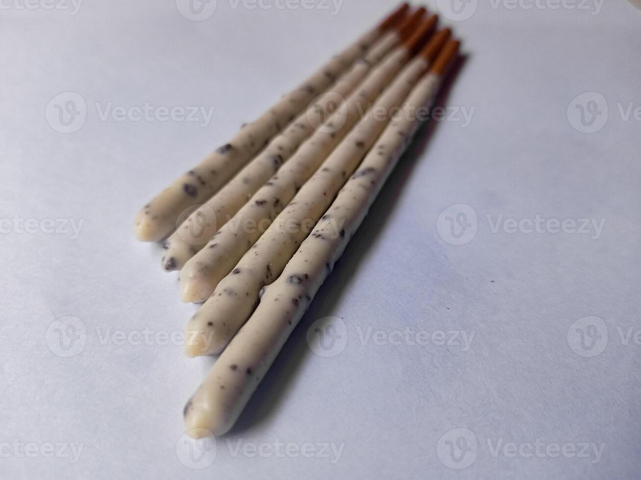 Chocolate biscuit stick coated with milk flavour confectionery and crushed cookies and cream taste isolated on white background. photo