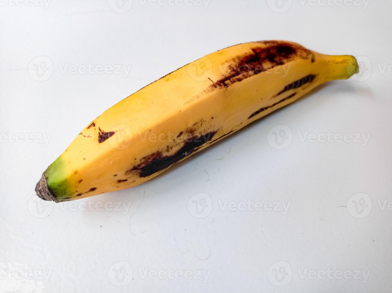 Ripe banana with brown spots on white background photo