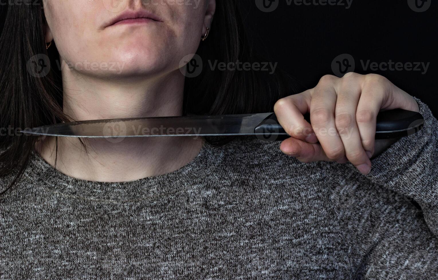 Girl brings knife to her throat, black background photo