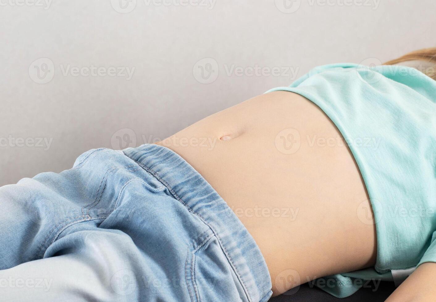 Pain in the lower abdomen in a seven-year-old girl. Inflammation of the bladder and urinary system, cystitis. Bacterial, close-up. Red stomach. Copy space for text photo