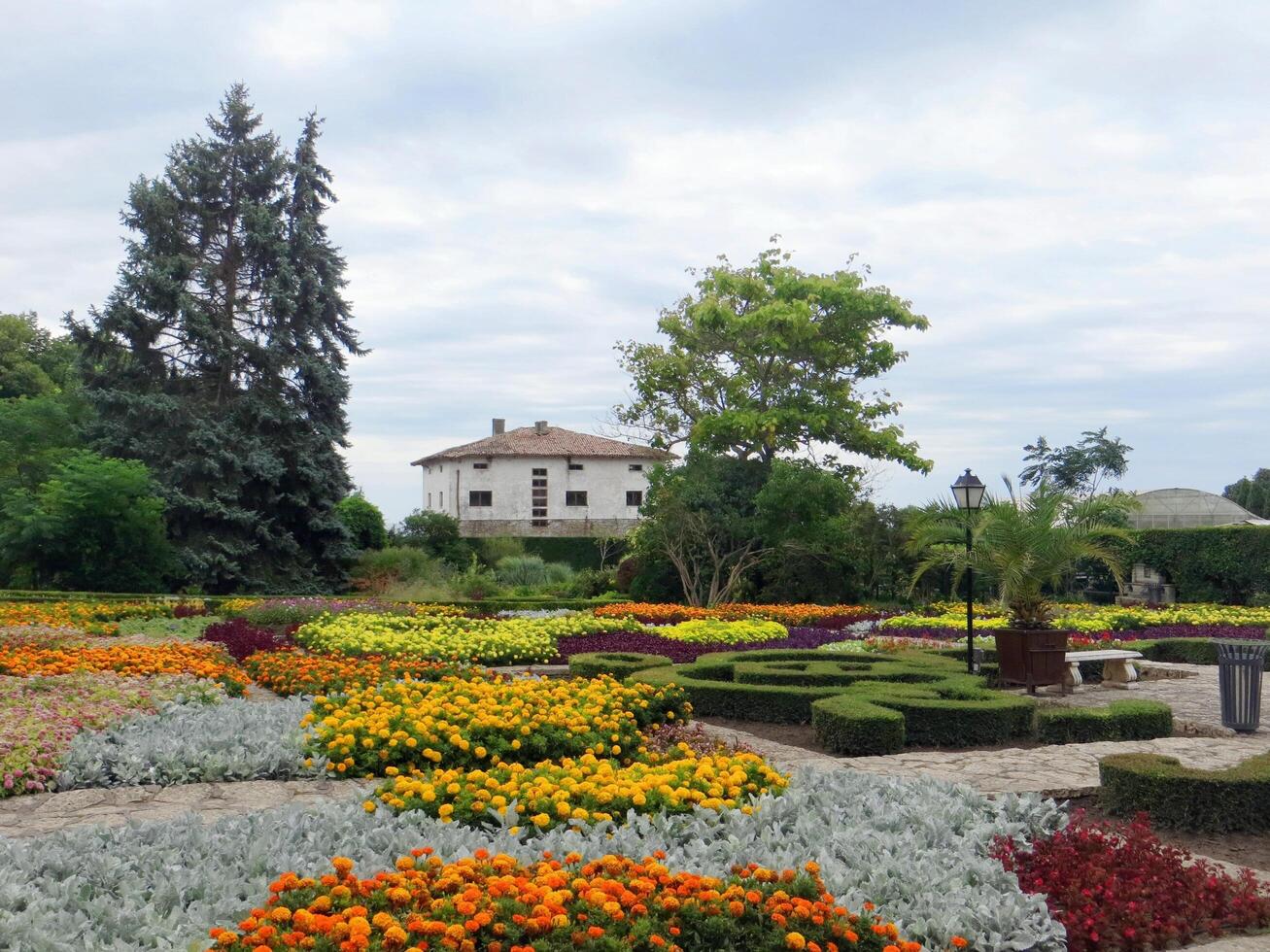 Balchik, Bulgaria. July 30, 2024. The botanical garden of the Queen Marie of Romania at Bulgarian Black Sea coastline. Colorful pattern of flowers with white cottage at the background.. photo