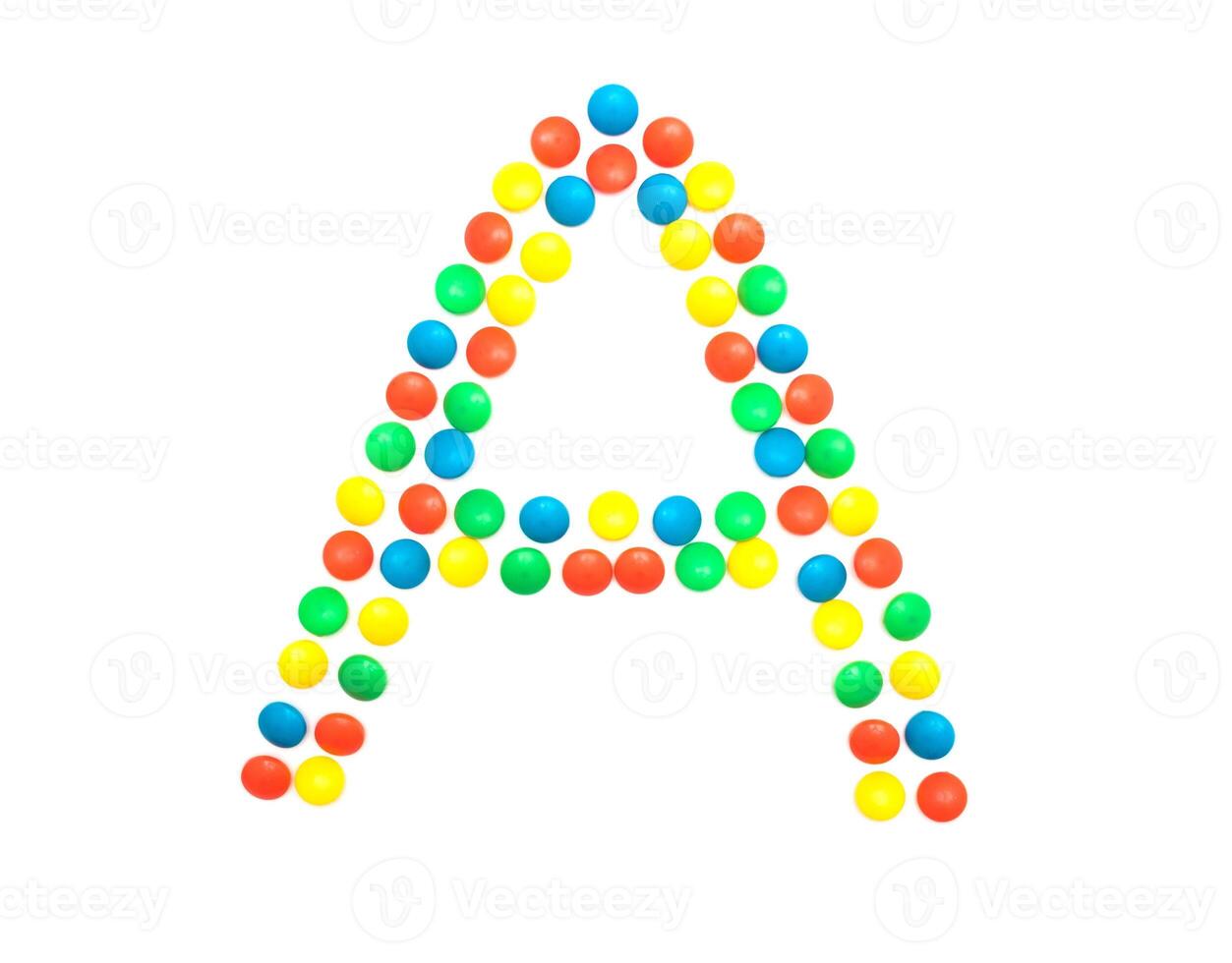 Multi-colored vitamins pills that are lined with the letter Vitamin group A, close-up photo