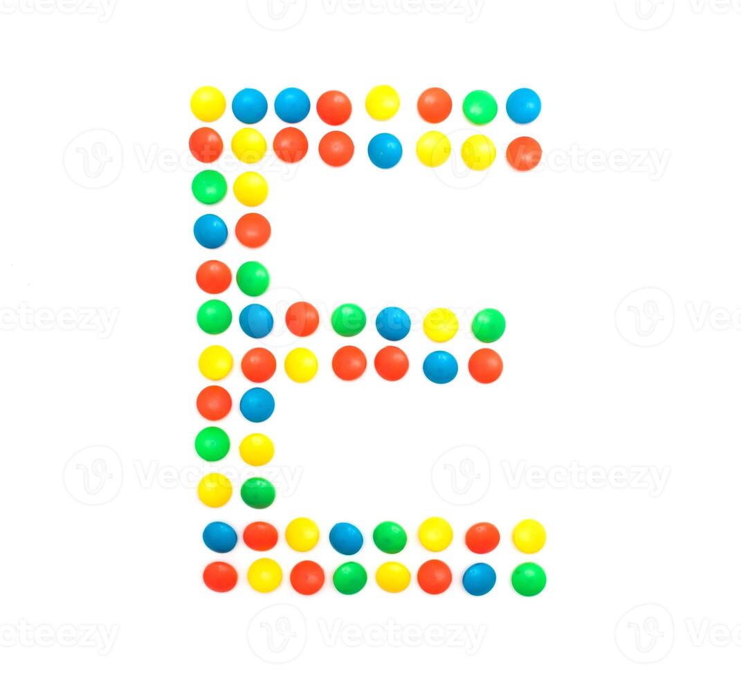 Multi-colored vitamins pills that are lined with the letter Vitamin E, close-up photo
