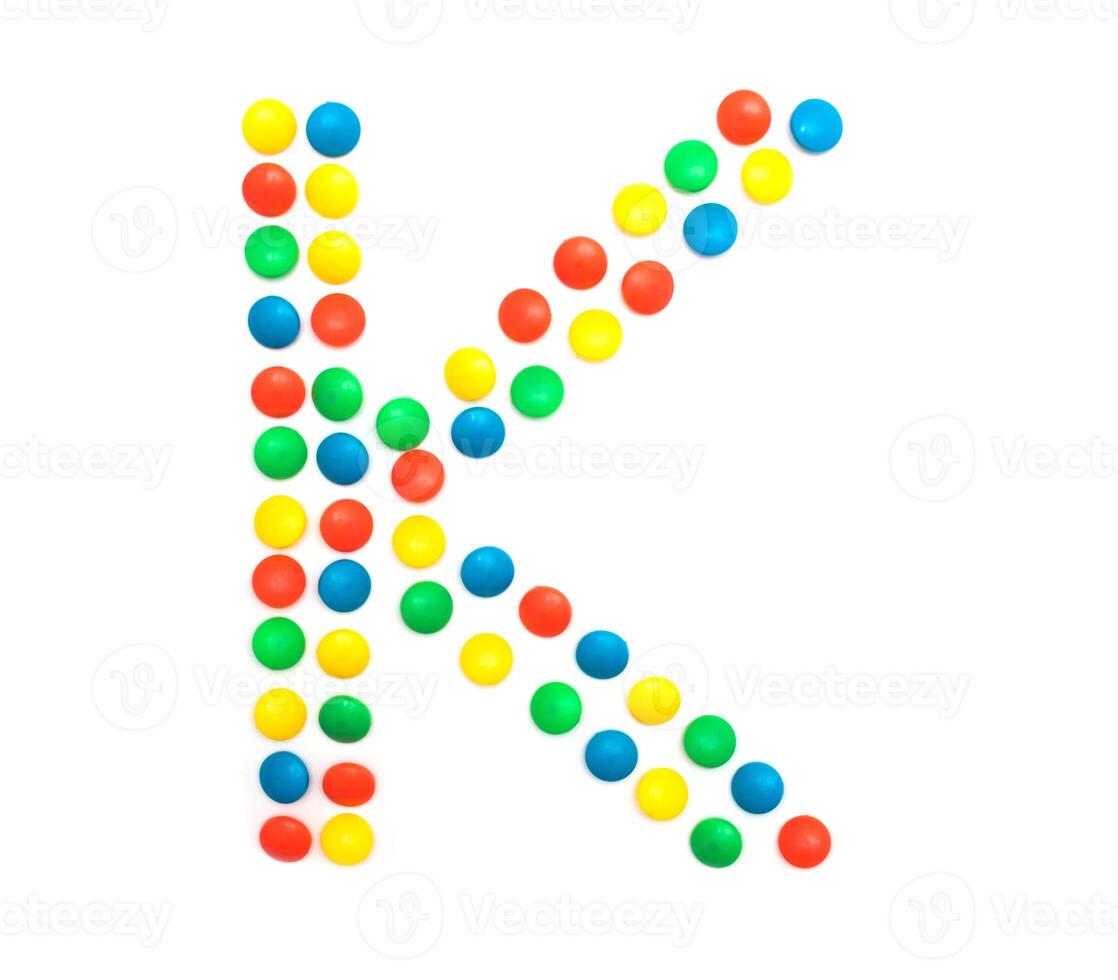 Multi-colored vitamins pills that are lined with the letter Vitamin K, close-up photo