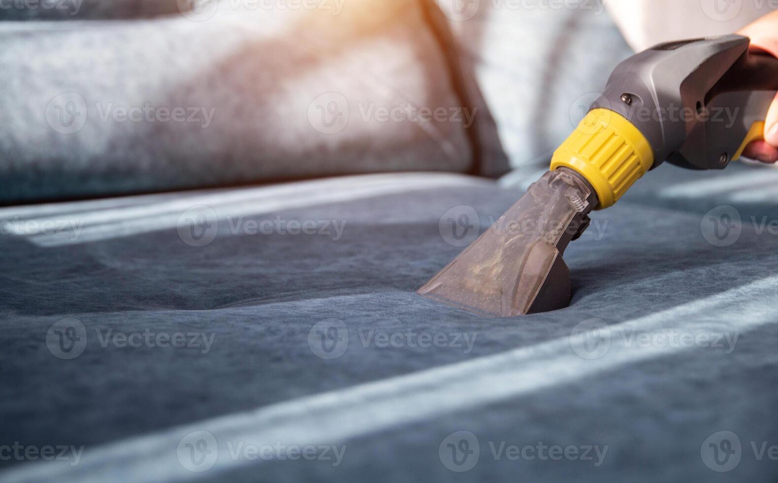 Cleaning a sofa with fabric upholstery from dirt with a professional vacuum cleaner, close-up. Copy space for text, chemical solution photo