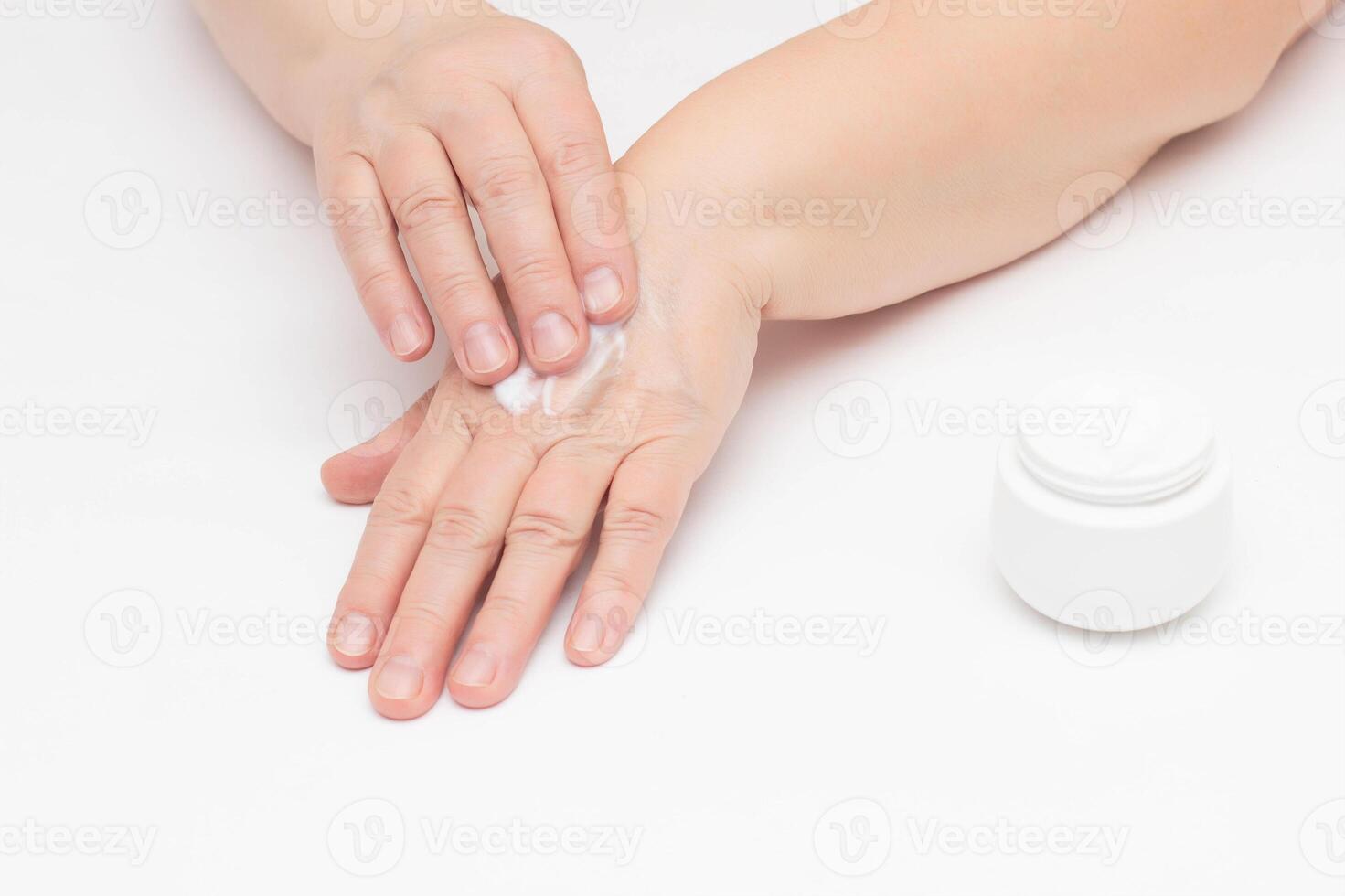 An elderly woman applies the cream on the problematic skin of the hands from irritation and redness on the skin, cream with vitamin for the hands, dermatology, relaxation photo