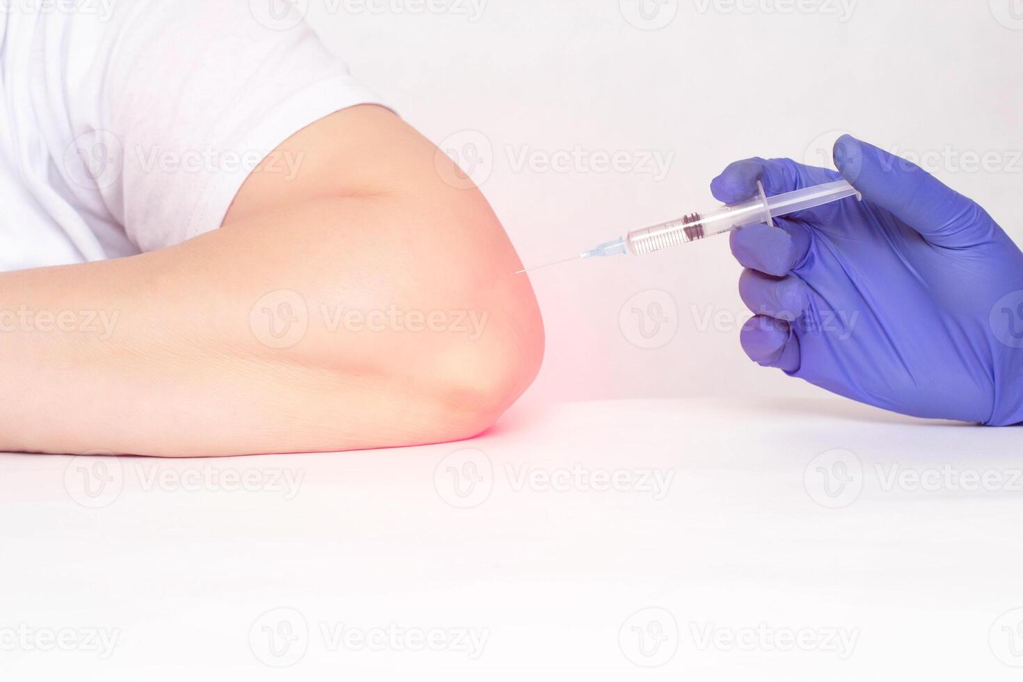A doctor makes an injection into the elbow joint of a woman who has pain and inflammation in the elbow joint, a concept of modern medicine, plasma therapy injections and hilauric acid photo