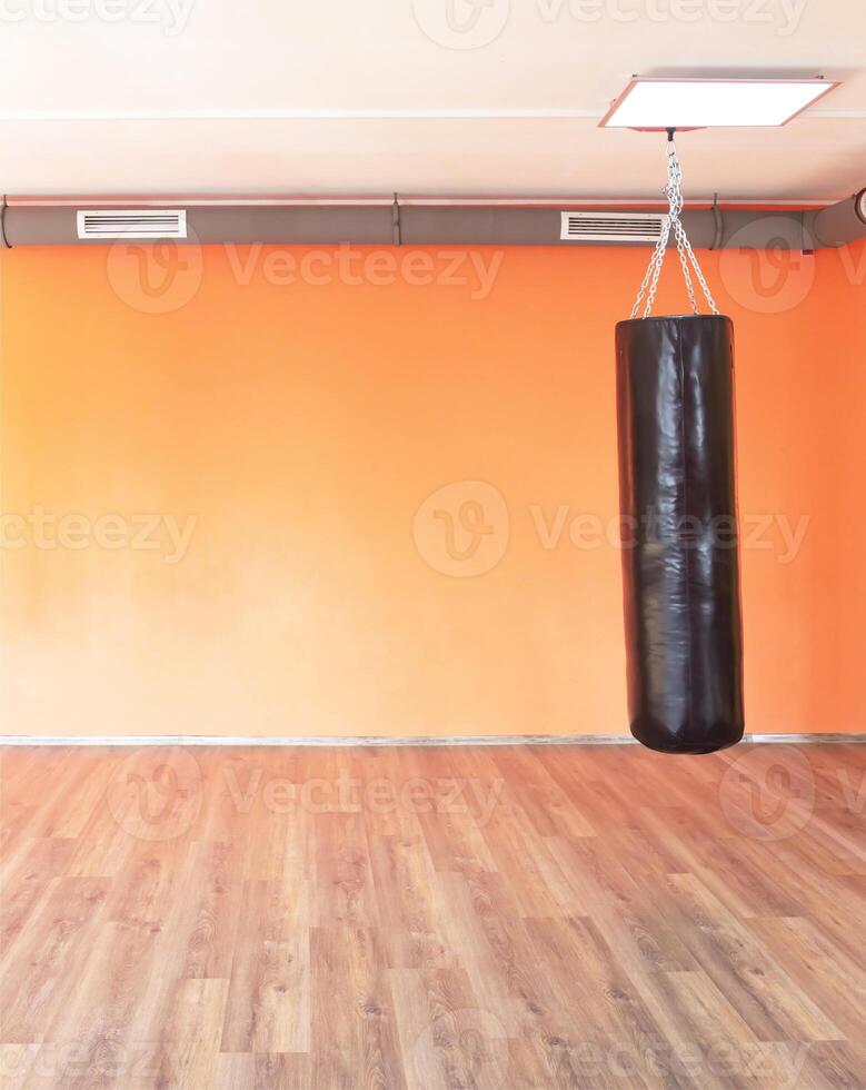 Boxing modern punching bag on the background of the orange wall in the new modern gym, copy space photo
