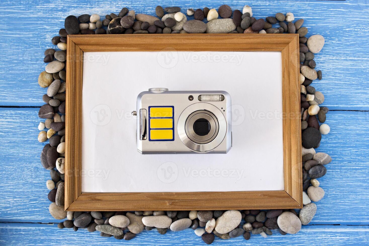 Clean frame on a blue wooden background, seashells and camera photo