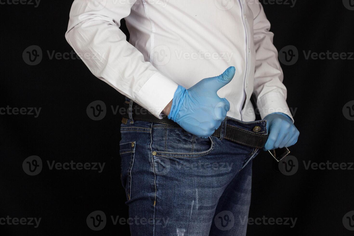 A man in a white shirt and jeans stares into his pants and shows a gesture class, okay, close-up photo