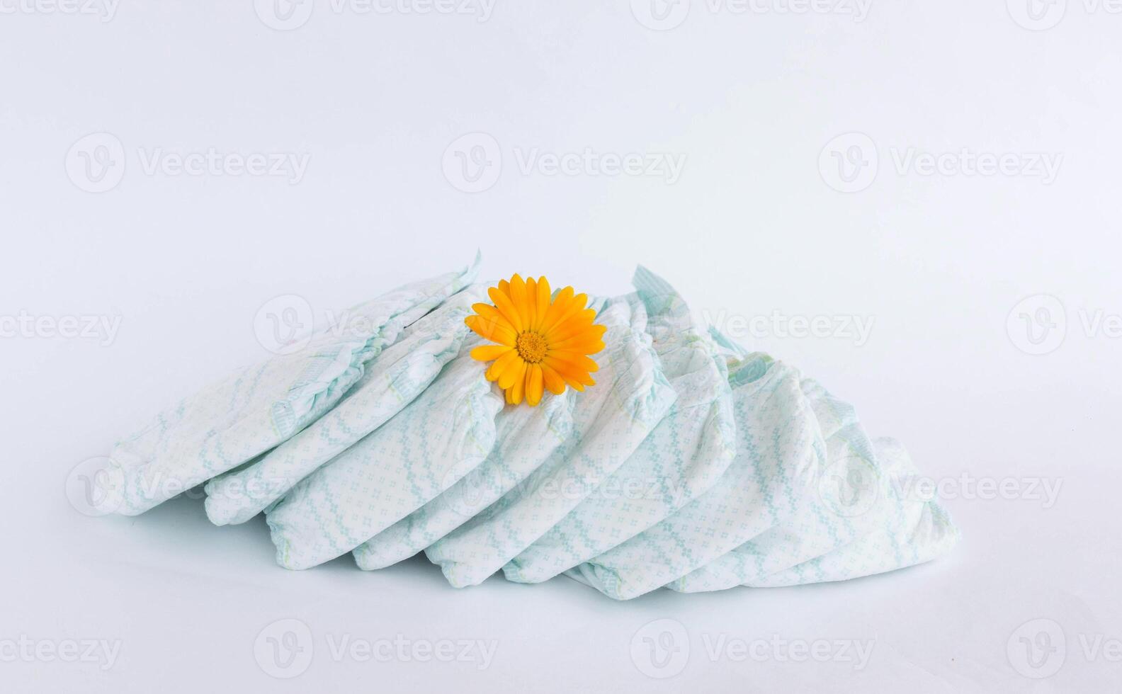 Baby diapers on a white background and an orange flower photo