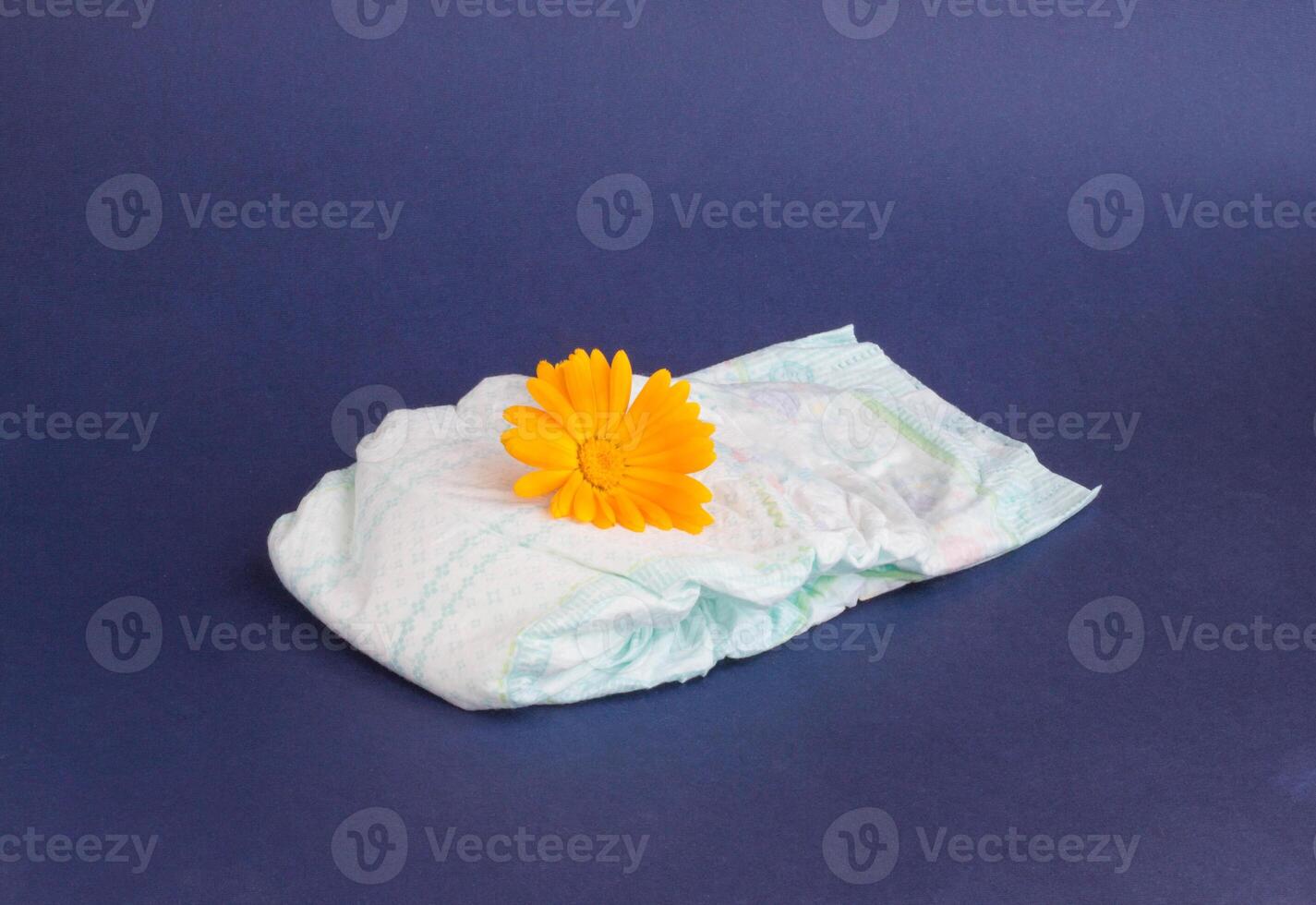 Baby diapers on a blue background and an orange flower on diapers photo