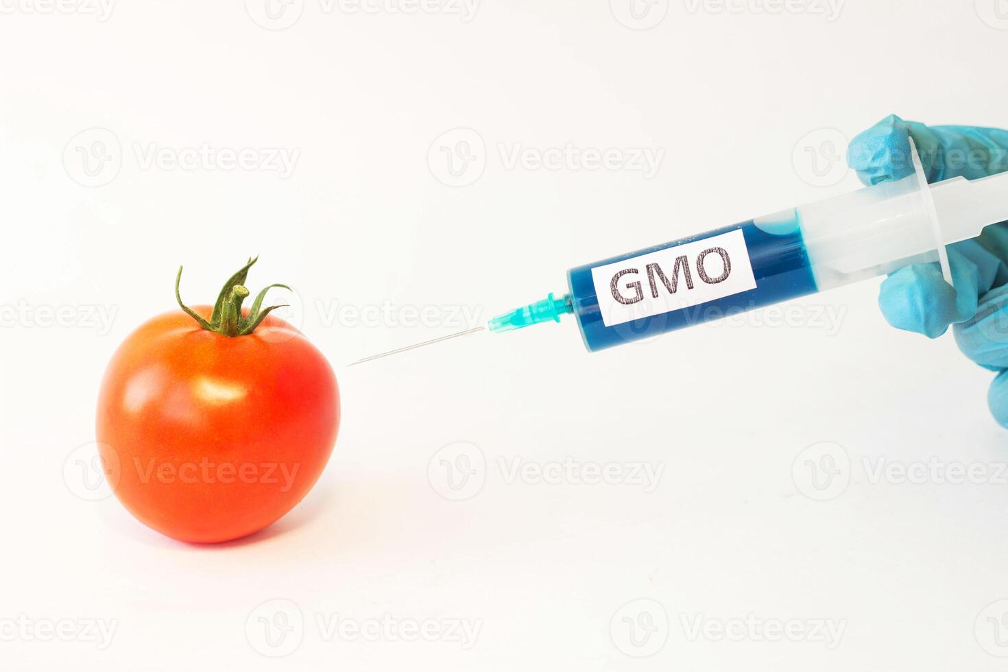 In a tomato on a white background from a syringe hand in a blue glove substance gmo, close-up photo