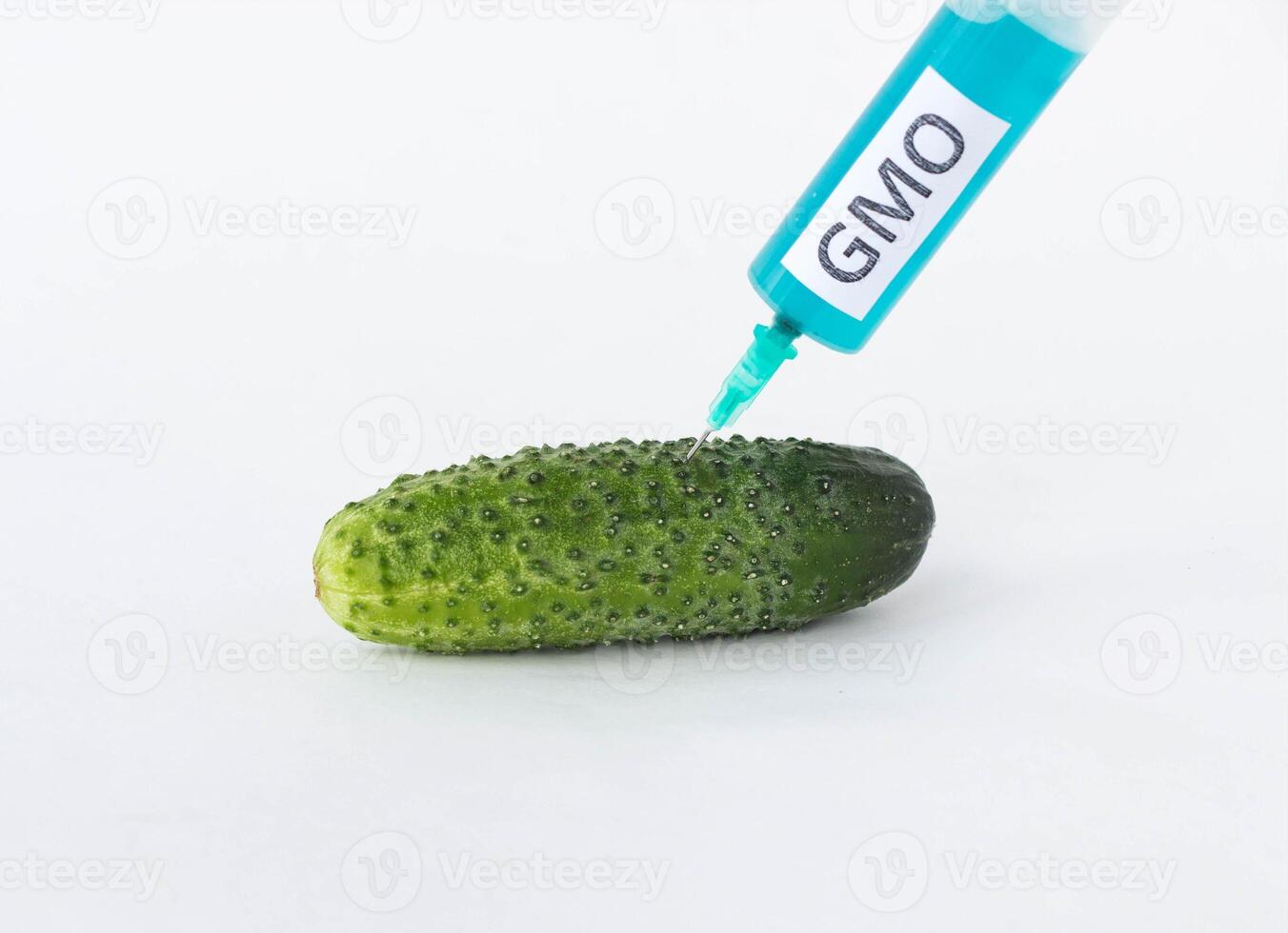 Cucumber on a white background in which the syringe gmo and nitrates are pricked, close-up, nitrates and genetically modified organism photo