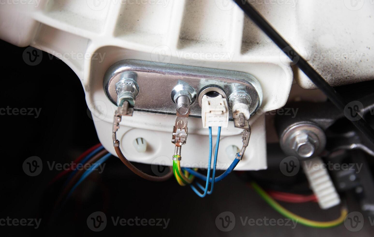 An electric heating element with a thermostat is connected with electrical chips. Repair and replacement of temperature sensor and heating element, hard water, close-up photo